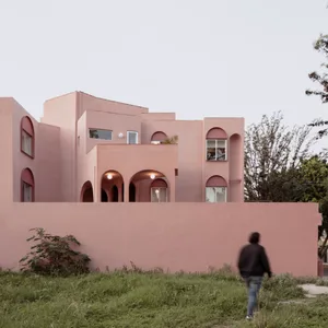 A modernist building with a concrete exterior features geometric shapes and a pink color scheme.