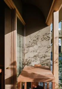 A wooden table with a concrete wall in the background, casting shadows.