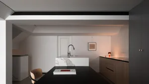 A modern minimalist kitchen with a marble countertop, stainless steel cabinets, and dark wood accents.