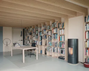 A modern home office featuring wooden walls and bookshelves filled with books.