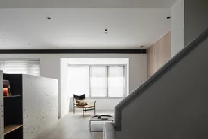 Modern interior space featuring a black and white terrazzo floor and a minimalist chair.