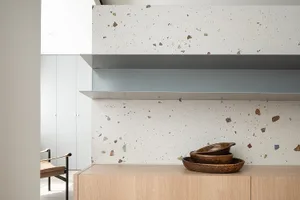 Modern minimalist interior with a terrazzo wall and floating shelves.