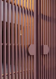 Close-up view of a metal fence with vertical slats and two circular handles.