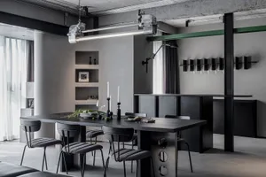 Industrial dining room with concrete walls and floors, featuring a modern dining table and chairs, and a wall-mounted wine gl