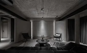Modern industrial-themed living room with concrete walls and black leather furniture.