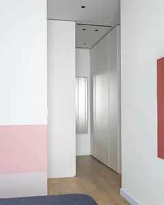 Modern bedroom with minimalist design featuring white walls and flooring.