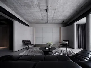 Modern industrial living room with concrete and cement walls, black leather furniture, and minimalist decor.