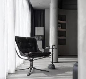 Modern room featuring a black leather chair, metal table, and concrete floor.