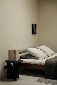 A minimalist bedroom featuring a wooden bed frame and white linens.