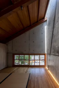 A modern minimalist living room with a concrete wall featuring a window with wood frames.