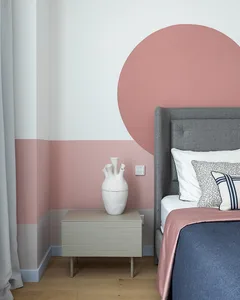 Modern bedroom featuring a gray upholstered bed, a blue and pink bedding set, a gray side table with a white ceramic vase, an