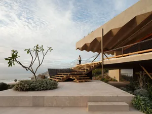 A modern concrete penthouse exterior with a geometric rooftop and ocean view.