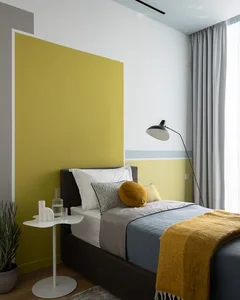 A modern minimalist bedroom with grey and yellow accents, featuring a grey bed with yellow and grey bedding, grey curtains, a