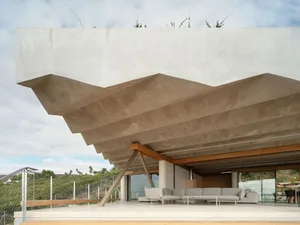 A modern residential terrace featuring a concrete structure with a large, open seating area.