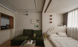 A minimalist bedroom featuring a green upholstered couch, a white bed with a curved headboard, framed art on the wall, and a 