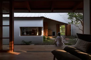 A minimalist living space featuring wooden materials and a view of a small garden or courtyard area.