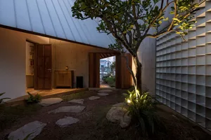 A modern, minimalist backyard with concrete elements, plants, and a tree.