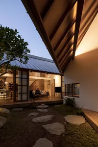 A modern house with a wooden exterior at dusk with illuminated windows.