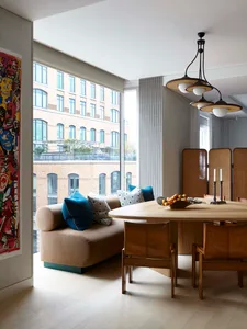 A modern living room with a cozy sofa adorned with cushions and a round wooden dining table surrounded by leather chairs, set