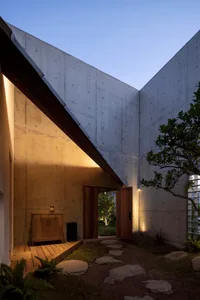 A modern minimalist exterior with concrete walls and a wooden roof in a residential area.