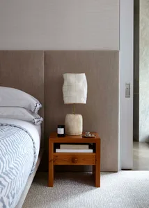 Minimalist bedroom with a wooden bedside table featuring a paper lamp.
