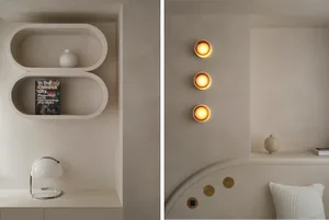 A minimalist bedroom with concrete walls, a white circular light fixture, and a white cushion.