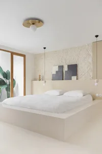 A minimalist bedroom with mixed materials, featuring a large bed with white bedding, a textured wall, and hanging light fixtu