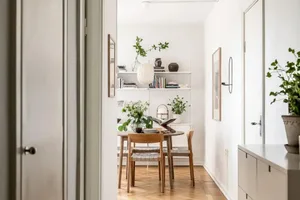 A minimalist dining room with a white interior, wooden floor, and a wooden table with chairs.