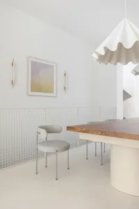 Modern minimalist interior design featuring a wooden dining table and chairs, minimalistic decor, and white walls.