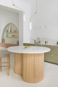 A minimalist residential kitchen with a white marble countertop and wooden textures. Includes a central island with a marble 