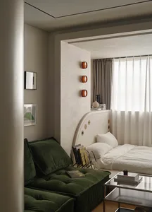 A modern bedroom featuring a bed with a fabric headboard and a glass coffee table with books and a candle.