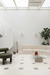 A minimalist living room featuring a concrete floor, curved sofa, and glass furniture.