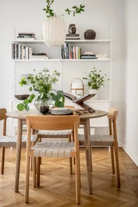A modern living room featuring minimalist decor, white walls, and an oak coffee table with woven leather stools.
