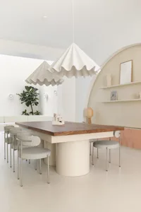 A modern, minimalist interior design featuring a wooden table. The space is characterized by clean lines, neutral colors, and