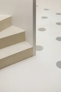 Modern minimalist white concrete stairs with circular cutouts on a white concrete floor.