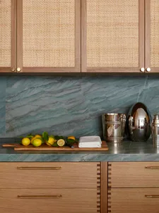 A modern kitchen featuring a marble countertop, wooden cabinets, and metal decorative items.