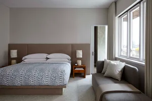 A contemporary bedroom furnished with a bed and a modern sofa, featuring a textured fabric headboard and sofa, and white and 
