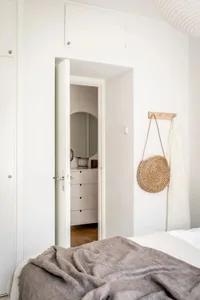 A cozy, minimalist bedroom featuring a woven basket, wooden furniture, and textured bedding.