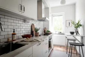 Modern, minimalist kitchen with white subway tiles, stainless steel appliances, and wooden accents.