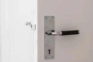 Modern metal door handle attached to a white door.