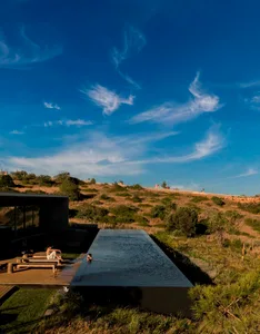 People lounging on a glass deck near a minimalist swimming pool.