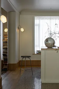 A modern apartment featuring minimalist design with wooden floors and a distinctive terrazzo counter, illuminated by warm sco