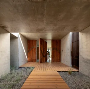 Modern architectural entrance featuring concrete walls and wooden flooring.
