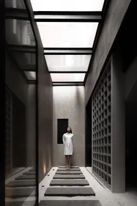 A minimalist interior space made of concrete and glass with a skylight.