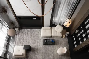 A modern living room featuring a white sofa, an armchair, a coffee table, and a bookshelf with magazines. The room has marble