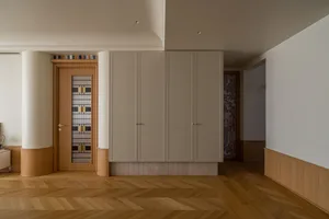 Modern living room with white walls, wooden floors, and minimalist furniture.
