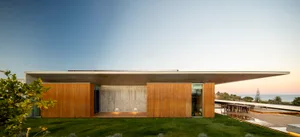 Modern residential exterior with a flat roof, concrete walls, and wooden accents.