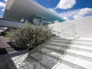 Modern residential exterior with marble steps, glass railings, and white marble wall.