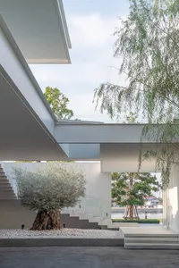 An indoor staircase with a concrete base surrounded by a gravel patio, leading to a green area with trees and a light blue sk