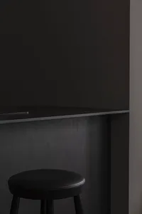 Black countertop with black stool against dark wall in minimalist interior